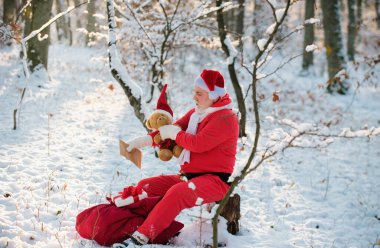 Noel Baba, hediye ve oyuncak ayıyla dilek listesi okuyor. Karlı kış dağlarında Noel Baba takım elbise giyiyor. Yeni yıl ve xmas geliyor.