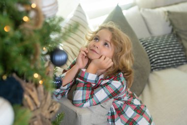 Noel 'i kutlayan küçük bir çocuk ya da evde Noel ağacı olan bir çocuk.