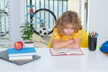 Okul çocuğu kitap okuyor. Okul çocuğu evde ders çalışıyor. Çocuk ödev yaparak ders çalışıyor. İlkokul ve evde eğitim. Uzaklık eğitimi kavramı