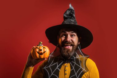 Cadılar Bayramı balkabaklı komik bir model. Cadılar Bayramı şapkalı balkabaklı insan portresi. Şeker mi şaka mı? Cadılar Bayramı şapkalı korkunç hippi. Cadı şapkalı adam balkabağını tutuyor. Komik Cadılar Bayramı