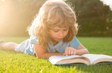 Çocuk tatilde rahatlar. Çocuk çim arka planı hakkında kitaplar okudu