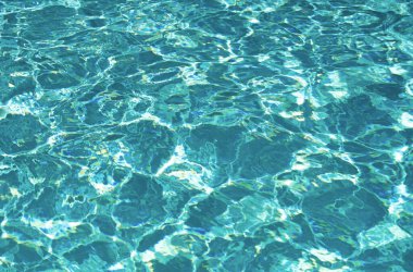 Yüzme havuzunda güneş yansımalı dalgalı su. Dalgalı su arkaplanı