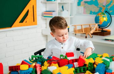 Erken gelişen çocuklar. Eğitici oyuncakları olan anaokulu çocuğu. Bloklar, tren, demiryolu, uçak. İlkokuldan bir çocuk