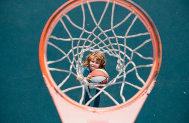 Oyun sahasında basketbol oynayan bir çocuğun üzerine açıyla bak.