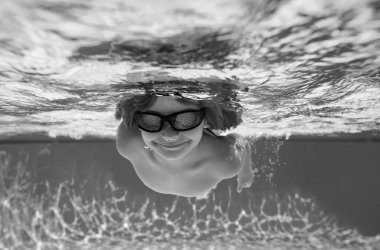 Havuzda yüzen bir çocuk. Komik küçük çocuk havuzda su altında yüzüyor. Suyun altındaki çocukların portresi. Yaz tatili. Çocuklar hafta sonu