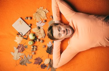 Zencefilli adam sonbahar satış günü için hazırlıyoruz. Sürpriz adam kameraya bakıyor. Adam portakal yaprağı arka plan üzerinde yatıyor ve ok göster. Turuncu yaprak zemin üzerine komik adam