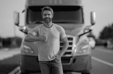 Kamyonun yanında erkek sürücü var. Kamyonun yanında bir kamyon şoförü var. Yakışıklı, orta yaşlı kamyoncu kamyoncu adam. Ulaşım endüstrisi araçları. Kamyonun önündeki yakışıklı adam.