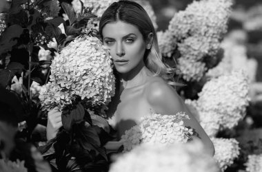 Yaz parkında çiçek açan ortancada poz veren şehvetli bir kadın. Rahatlama, seyahat, özgürlük ve bahar tatili kavramı. Moda tarzı. Romantik ve yaşam tarzı kavramı