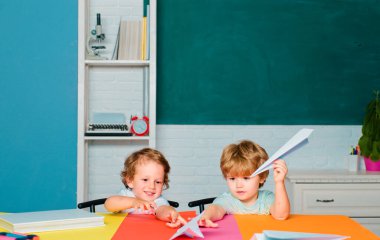 Çocuk sınıfta tahtayla ilgili bir şeyler öğreniyor. Okul malzemeleriyle masasının yanında gülen surat ifadesi olan küçük bir çocuk. Okul bahçesindeki ilkokuldan erkek öğrenci.