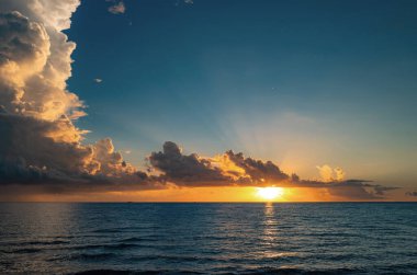 Tropikal deniz okyanusunda gün batımı ve gündoğumu bulutları. Seyahat tatili afişi. Manzara gökyüzü ve yansıma ışınları. Pasifik Okyanusu. Sahilde gün batımı. Renkli okyanus plajı gün doğumu