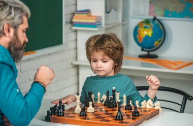 Babası olan çocuk evde satranç öğretiyor ve öğreniyor. Öğretmen ve çocuk. Baba oğul evde satranç oynuyor.