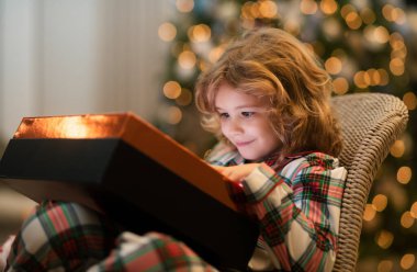 Noel Baba 'nın kırmızı şapkalı çocuğu Noel hediyesi taşıyor. Noel ve Yeni Yıl konsepti. Sürpriz çocuk hediye kutusunu açıyor.