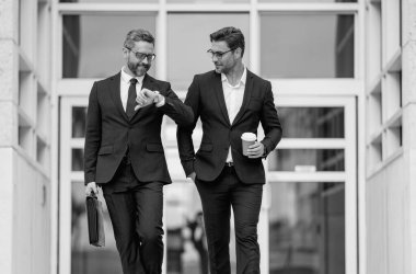 İki iş adamı. İki iş adamı takımı için pazarlama stratejisi. Ticari satış stratejisi gelirde etkiliydi. Takım elbiseli bir adam Amerikan ofisinin önünde yürüyor.