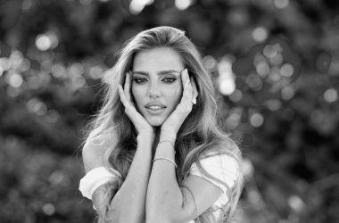 Baharın tadını çıkaran güzel bir kadın. Bahar yeşili doğada çekici romantik bir kız. Cazibeli genç bir kadın açık hava portresi yapıyor.