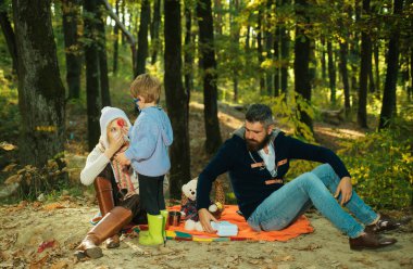 Autumn Park 'taki şehvetli aile fotoğrafı. Oğlum, anne babasıyla doktorculuk oynuyor. Sonbahar mevsimi ormanda güneşli günler. Sonbahar mevsiminde rahat sonbahar kıyafetleri içinde birlikte yürüyen aile portresi.