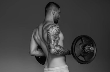 Handsome fit muscular caucasian man workout in the gym with weight pumping up muscles. Fitness and bodybuilding sport. Bodybuilder with dumbbells at gym, hard workout