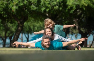 Doğada eğlenen çocuklu genç bir aile. Sinek konsepti, küçük çocuk uçuşu taklit ederken kazma gibi oturuyor. Seyahat hayali
