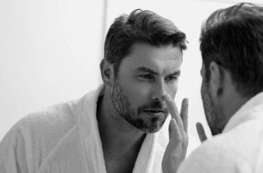 Yüz kremi süren güzel bir adamın güzel yüz portresi. İnsan için nemlendirici cilt kremi. Maske, deri değiştirme ve yaşlanmayı önleyici etki. Güzel erkek yüzü konsepti. Cilt bakımı ve yaşlanma. Yüz Kozmetiği