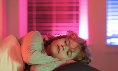 Gece uykusu. Çocuk yatakta uyuyor. Çocuk battaniyenin altında uyuyor, yastığın üzerinde yatıyor. Çocuk uyuyor, sağlıklı bir uyku çekiyor ya da kestiriyor.