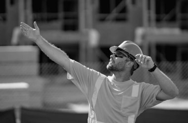 İnşaat alanında kasklı bir miğfer var. İnşaat inşaatında mühendis üniforması. İnşaat binasının yakınında. İnşaat alanındaki inşaatçının portresi yeni bir ev inşa ediyor.