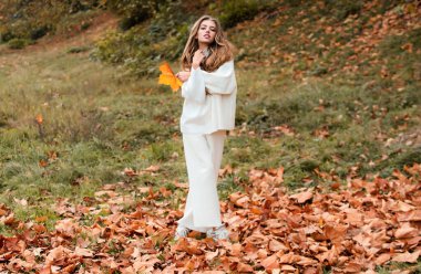 Sonbahar modası. Şehir parkında modern elbiseler giyen genç ve şık hippi kız mutlu bir şekilde gülümsüyor. Kafkas kadın modeli. Sonbahar modası