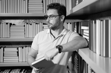 Kütüphanede kitap okuyan bir öğretmen. Öğretmenler günü, öğretmenler günü. Bilgi, eğitim. Kütüphanede ders veren bir öğretmen. Üniversite kütüphanesi. Öğretmenler edebiyat okuyor