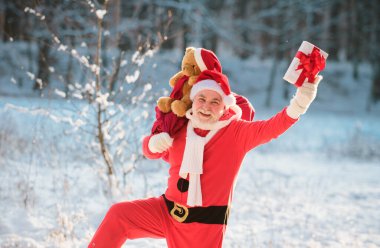 Mutlu Noel Baba kış ormanına hediye dolu bir çanta ve kar manzarasıyla geliyor.