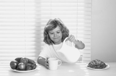 Cute child pouring whole cows milk. Portrait of child eat fresh healthy food in kitchen at home. Kid boy eating breakfast before school