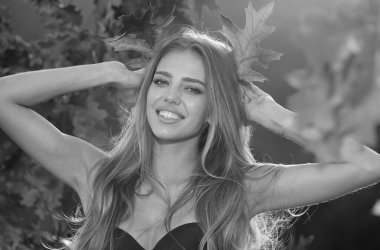 Sonbaharda güzel bir kız. Genç kadın sonbaharda sarı sonbahar yaprakları topluyor. Güzel kadın, sonbahar sarısı yaprağını tutar ve yüzüne düşer. Sonbahar döneminde şehvetli bir kadının portresi.