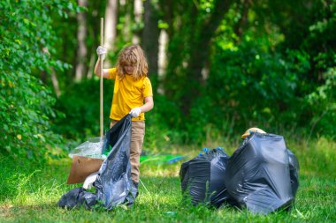Küresel çevre kirliliği. Çocuk dışarıda plastik çöp topluyor. Çevre koruma kavramı. Çocuk çöp torbasına atık koyuyor. Eko çocuklar gönüllü. Çevre kirliliği