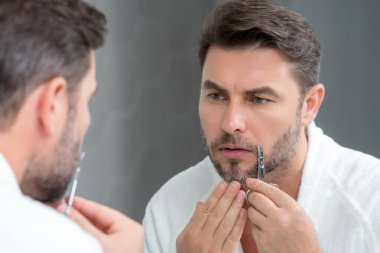 Makaslı adam. Adam kuaför makasıyla saç kesiyor. Stüdyoda erkek tıraşı. Berber makası. Erkekler sakal keserler. Elinde makas tutan adam.