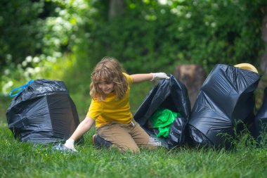 Çocuk dışarıda çöp topluyor. Ekoloji konsepti. Çevre kirliliği. Dünya Günü. Çöp tenekelerini geri dönüşümle temizleyin. Doğa temizliği. Çevre plastik kirliliği