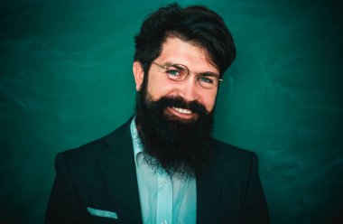 Öğretmenler zorluklar ve ilham. Okulda ki sakallı profesör sınıftaki masalarda. Okul sınıfında tebeşir tahtası yakınında genç sakallı öğretmen