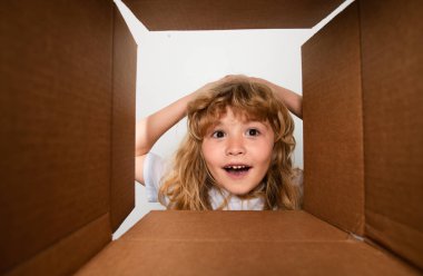 Komik heyecanlı çocuk kutuları açıyor ve kutunun içine bakıyor. Küçük çocuklar içeride boks hediyelerini açıyor. Çocuklar için kutu ve teslimat paketini aç