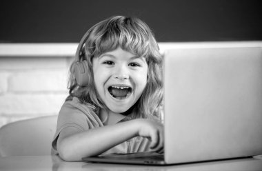 Zeki, heyecanlı okul çocuğu, hayrete düşmüş öğrenci kulaklık takıyor dizüstü bilgisayarda yazıyor, müzik dersi alıyor bilgisayar kullanıyor.