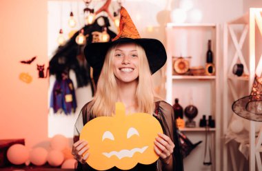 Halloween cadı siyah şapkalı. Kadın kabak ile poz. Sevimli genç cadı Cadılar Bayramı partisinde kapalı portresi. Bir peri kabak ile genç ve güzel sarışın kadın kılığında. Helloween insanlar kavramı