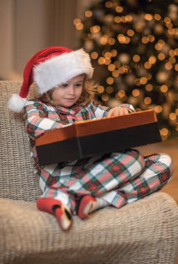 Noel Baba şapkalı çocuk evde Noel ağacının yanında.