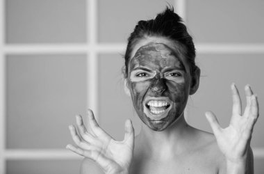 Kadın evde izole edilmiş kömür maskesi takıyor. Spa, kozmetik maske. Siyah kilden maskeli güzel bir kadın. Cilt bakımı, kabuk soyma, nemlendirici ve güzellik tedavisi