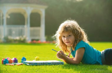 Çocuklar dışarıda resim çizerler, çocuklar yaratıcılığı resmederler. Çocuk arka bahçede ya da bahar parkında resim çizmekten zevk alıyor. Çocuklar dışarıda kalemle çizim yapıyorlar.