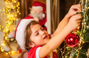 Güzel bir kadın Noel ağacını ziynetle süslüyor. Yeni yıl geleneğiyle. Noel çocuğu süslemesi ya da Noel balosu. Yeni yıl ve Noel çocukları konsepti