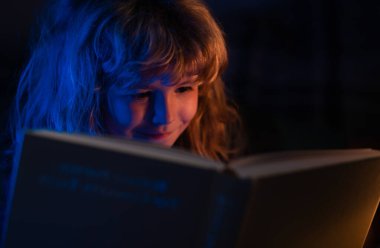 Çocuk kitaptan masal okuyor. Kitap okuyan şirin bir çocuk. Açık kitabı olan bir çocuk. Ev okulu dersi. Evde kitap okuyan konsantre küçük çocuk.