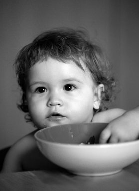 Mutfakta kaşıkla yemek yiyen komik bebek.