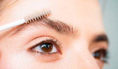 Kaşlar kapanır. Güzel kız kaşına jöle sürüyor. Kaşlarını doğal makyajla yapan beyaz bir kadının yakın portresi. Profesyonel kaş makyaj konsepti