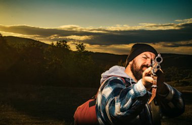 Hunter avı av tüfeği silahla. Avcılık dişli - av malzemeleri ve ekipmanları. Silah tutan ve ormanda yürüyüş sakallı avcı adam