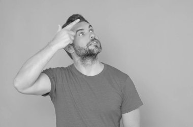 Nokta yukarı. Yukarı bak. Mutlu, yakışıklı bir adam pembe bir arka planı işaret ediyor. Heyecanlı adam harika bir fikir işaret ediyor. Mavi tişörtlü adam parmağıyla işaret ediyor.