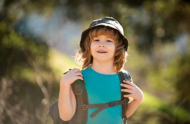 Sırt çantalı küçük bir çocuk manzaralı dağlarda yürüyüş yapıyor. Çocuk yerel bir turist yerel bir yürüyüşe çıkıyor..