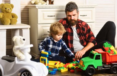 Father and son create toys from bricks. Dad and kid build of plastic blocks. Father and son playing toys wooden blocks on floor in living room