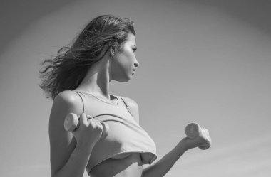 Atletik kadın halterlerle kaslarını şişiriyor. Kadın spor vücudu. Dişi kaslı kız. Dambıllarla çalışan seksi bir kadın. Sportif seksi kaslı kız.