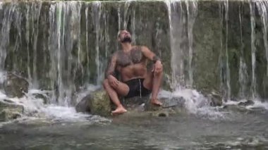 Alps şelalesindeki adam. Seksi bir adam. İnsan özgürlüğü yaşam tarzı. Doğada meditasyon. Yaşam tarzı doğa, yazları doğa. Sakinlik ve doğada rahatlama. Güçlü gövdeli güçlü adam, dışarıda banyo yapmaktan hoşlanıyor.