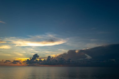Dramatik gün batımı gökyüzü. Deniz. Bulutların arasından gün batımını izleyen sakin bir deniz. Günbatımı okyanusu ve gökyüzü arka planı. Huzurlu deniz manzarası. Günbatımı deniz suyunun üzerinde bir ufuk. Güneşin doğuşuyla sakin deniz